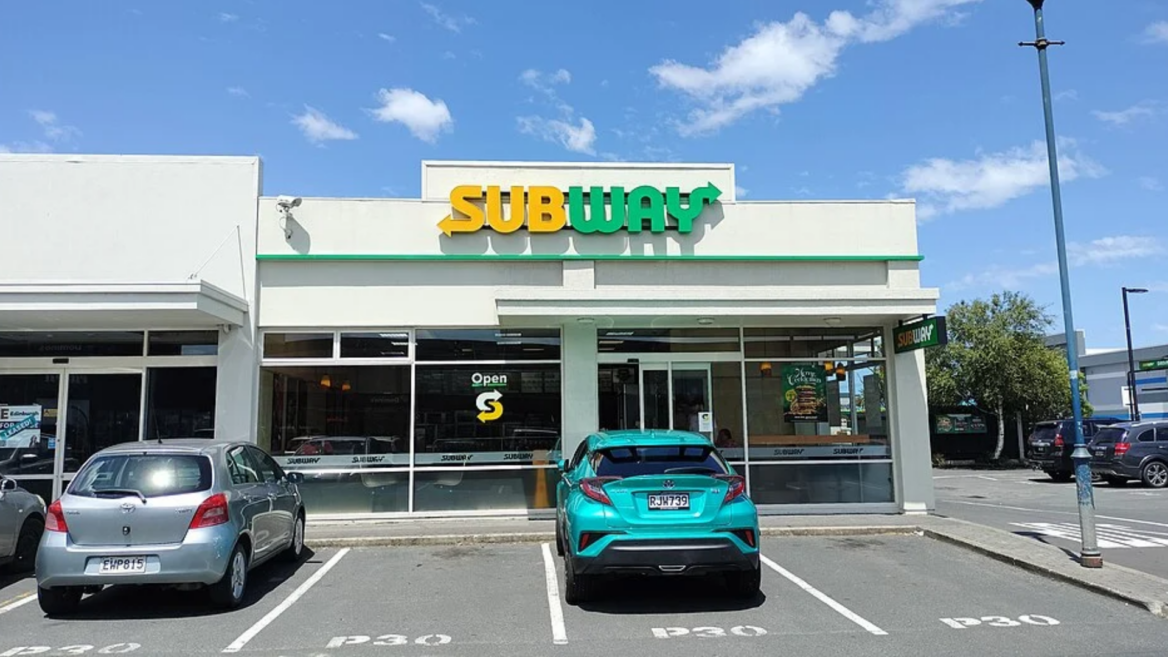 sunny subway storefront with parked cars