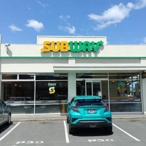 sunny subway storefront with parked cars