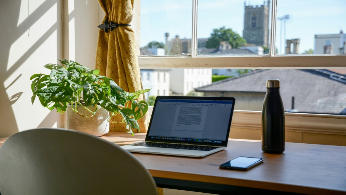 sunlit home office with laptop and window view