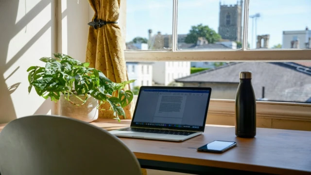 sunlit home office with laptop and window view