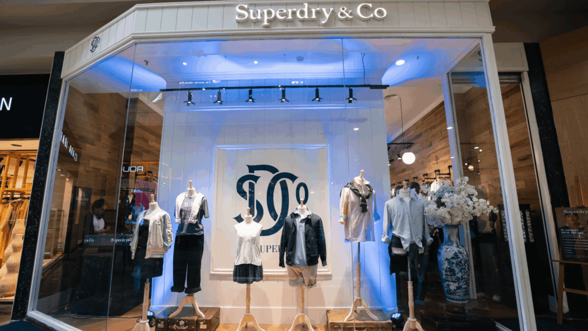 vitrina superdry en centro comercial con maniquíes y luces azules