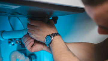 under sink plumbing repair with hands tightening fitting