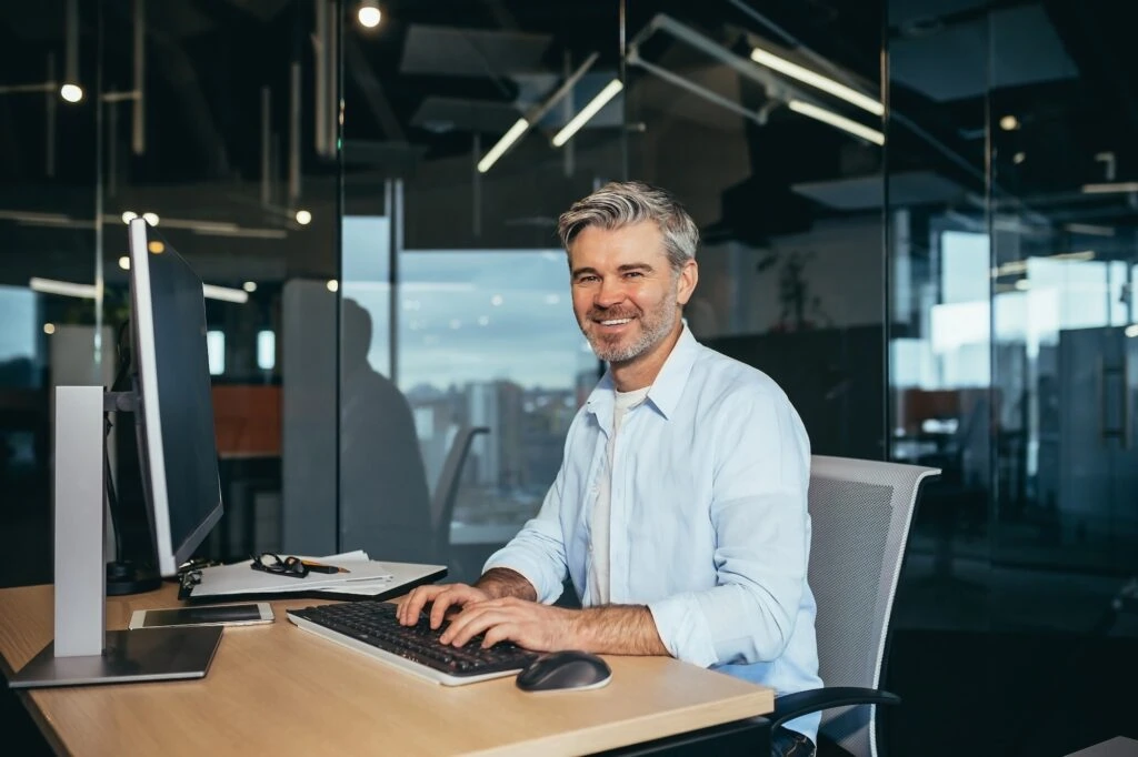 portrait of a successful businessman man rejoices and smiles works at the computer 1024x682